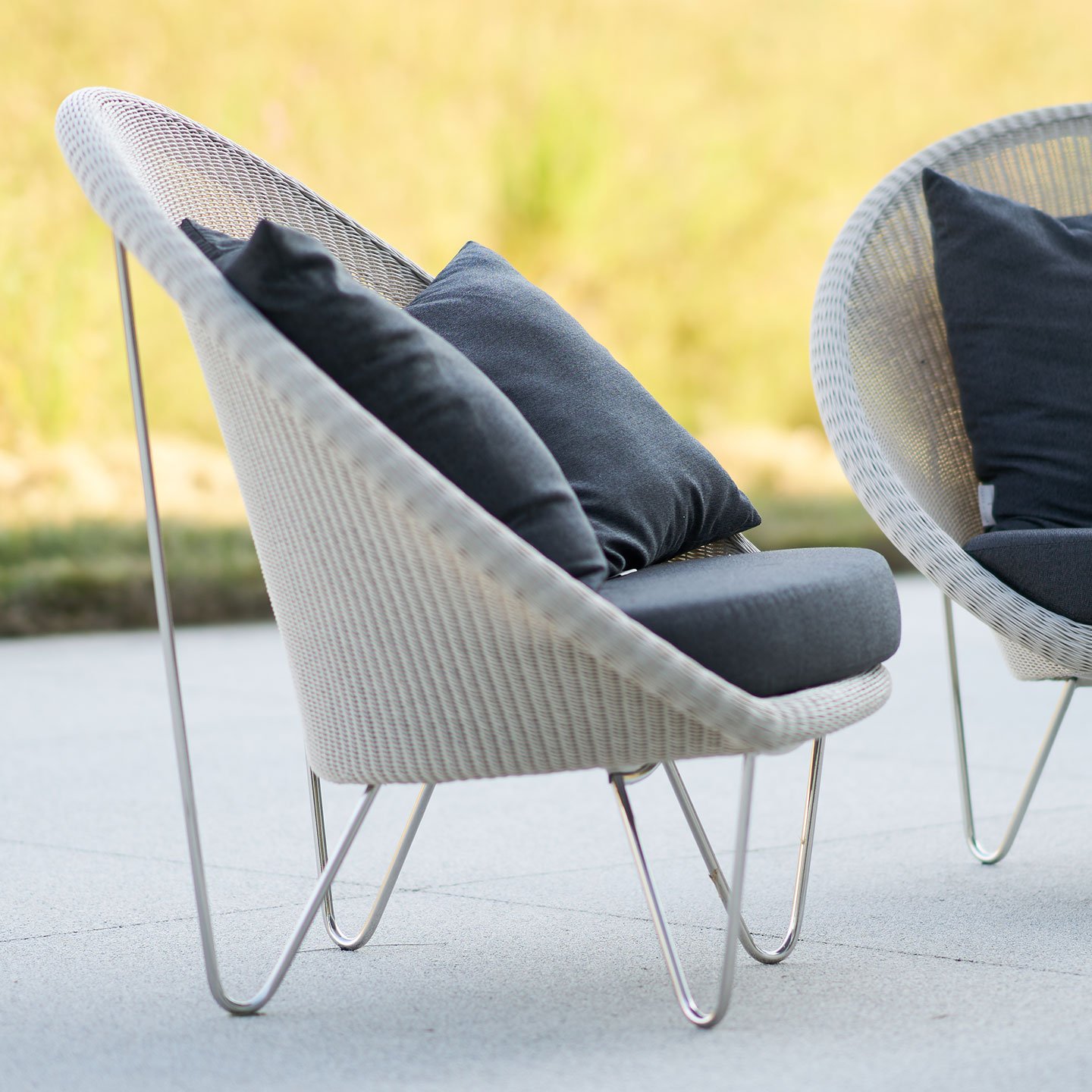 Haworth Gigi II lounge chairs in off white color with black cushions in an outdoor space side view