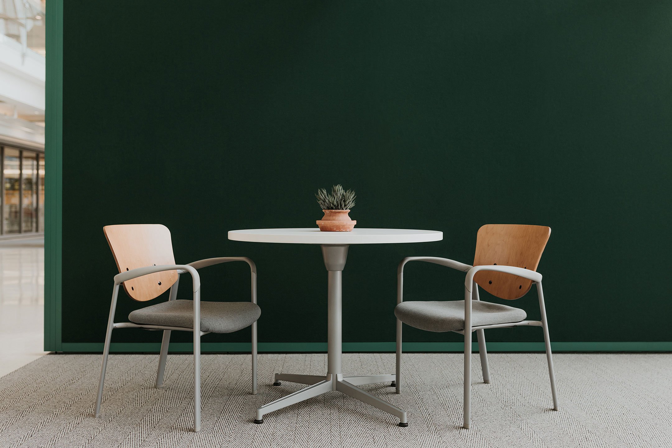 Haworth Improv Side chair in grey upholstery and wooden back at a coffee table