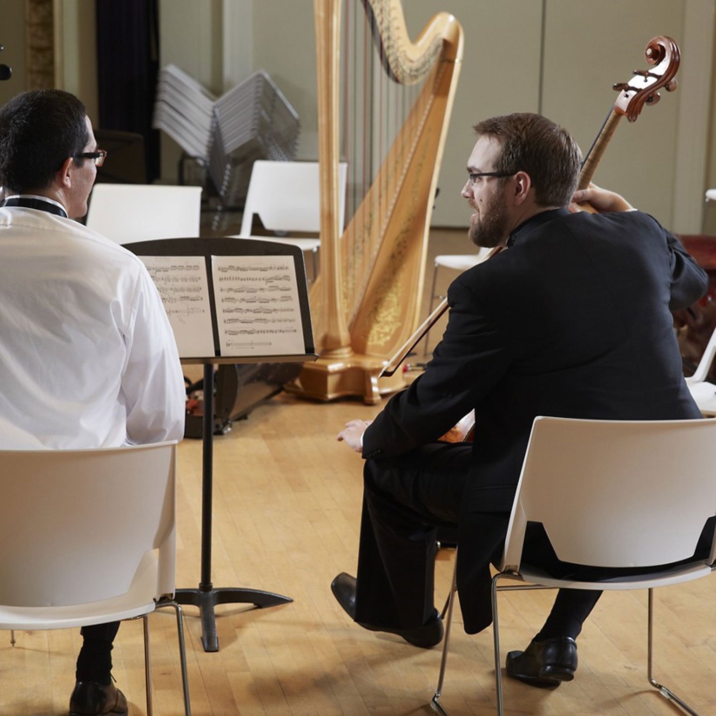 Two white Very Wire chairs on stage with Orchestra musicians 