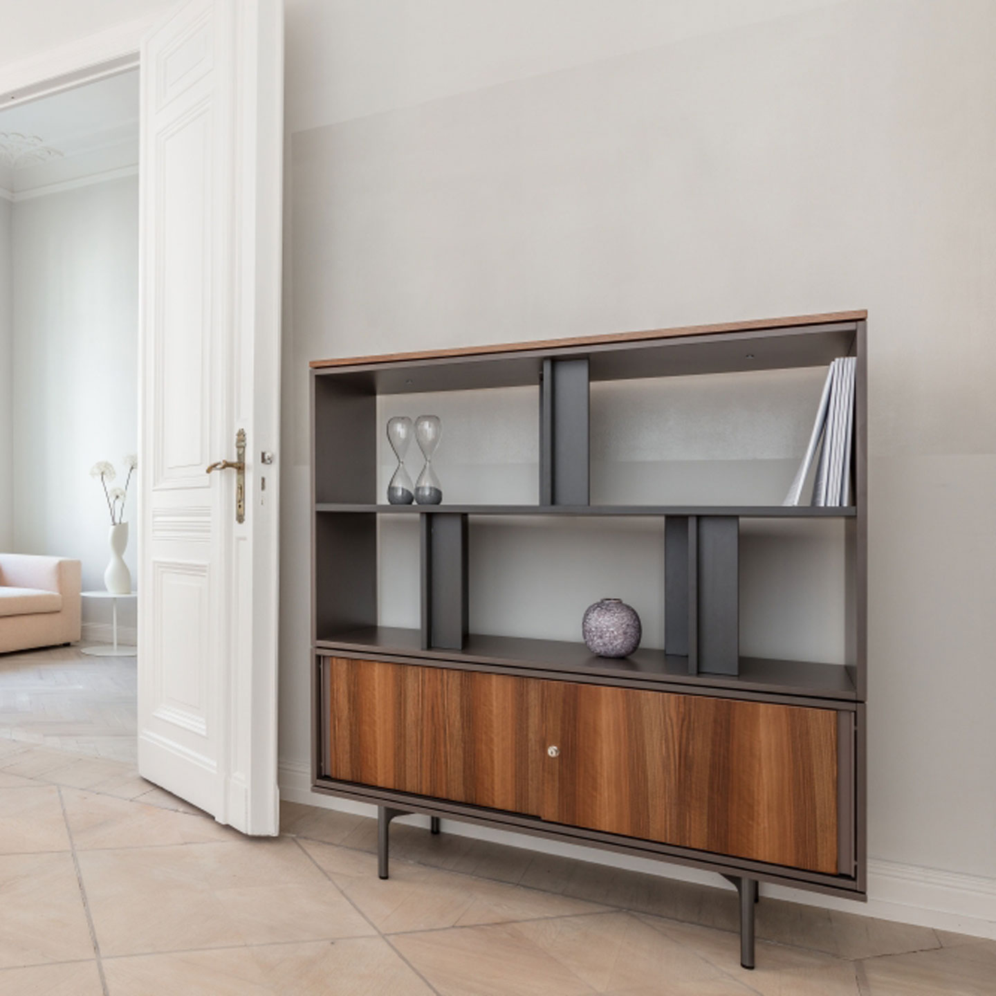 Be_Hold storage unit with open bookshelves in black with wooden sliding cabinets on lower level. 