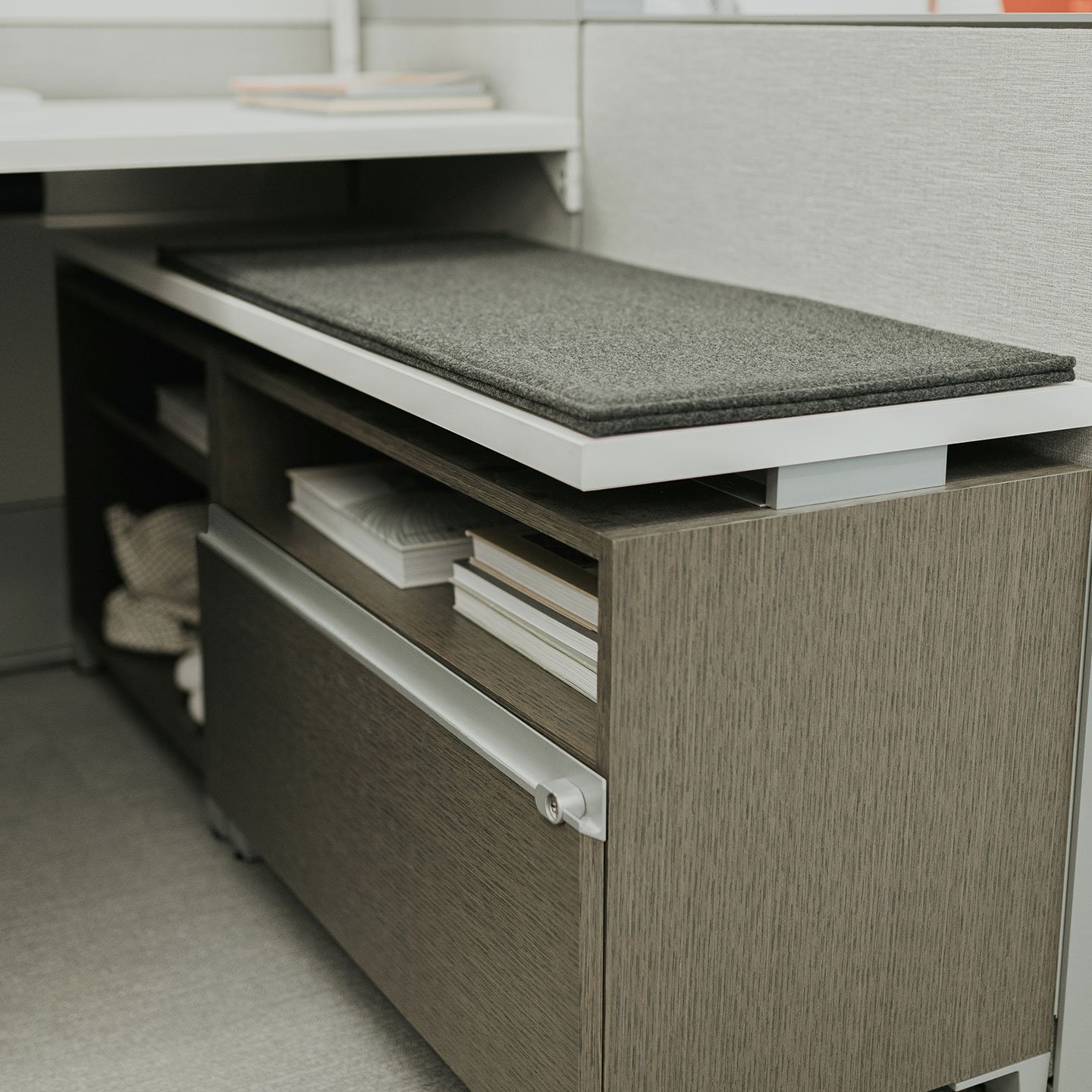 Compose storage unit with open shelf and file drawer with cushion on top. 