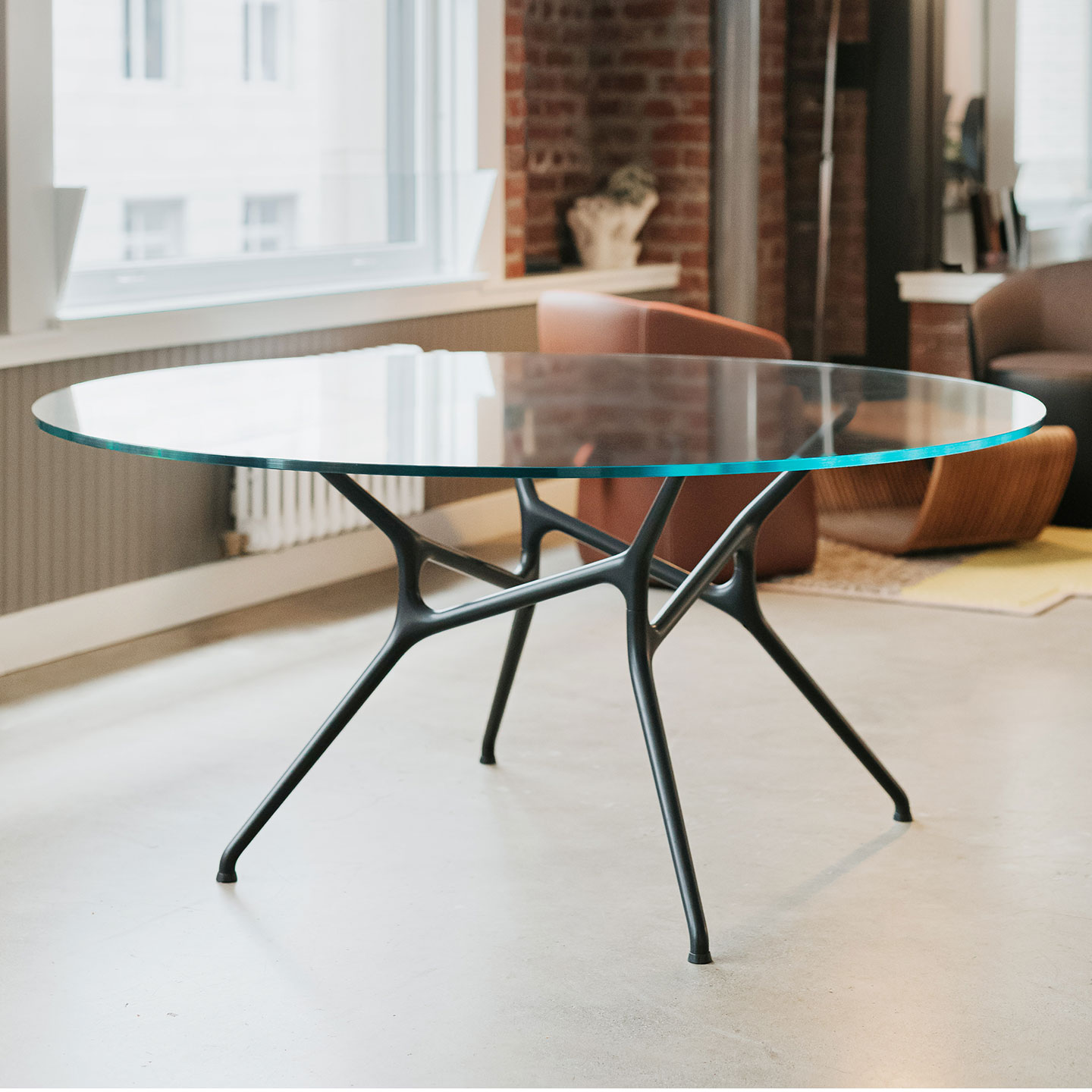 Haworth Branch table with circular clear glass top in a casual area next to a window