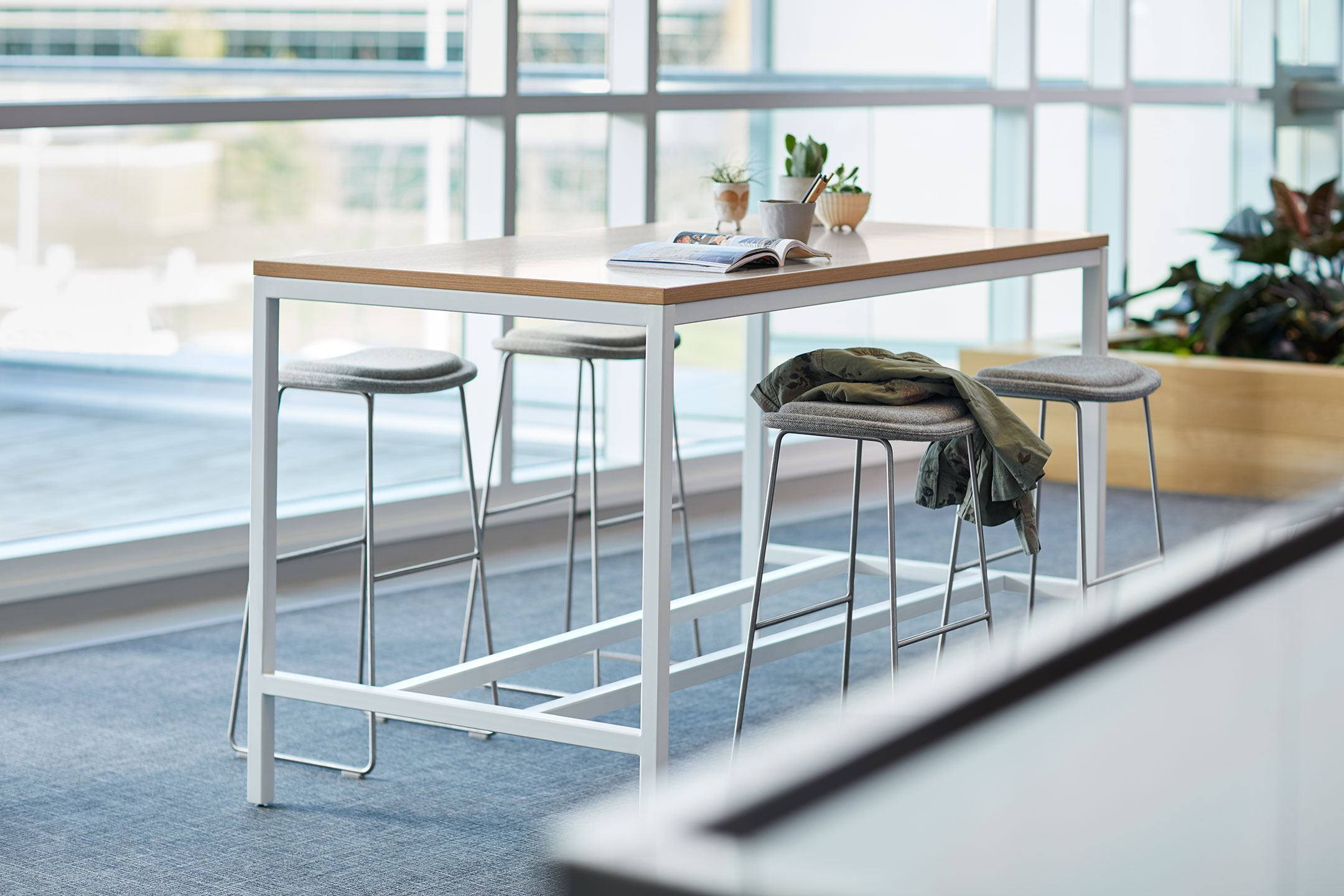 Haworth Cultivate table with 4 white legs and a rectangular veneer top in a work area by windows