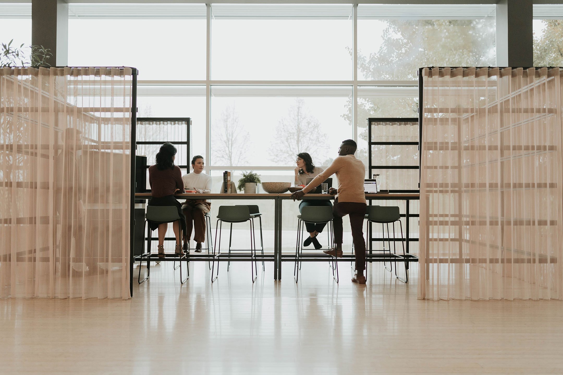 Haworth Cultivate table with 4 black legs and veneer top in a closed off collaboration area