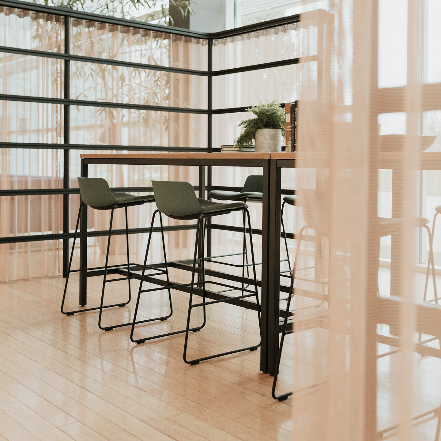 Haworth cultivate table with 4 black legs and vaneer rectangular top in a closed collaboration area with high chairs