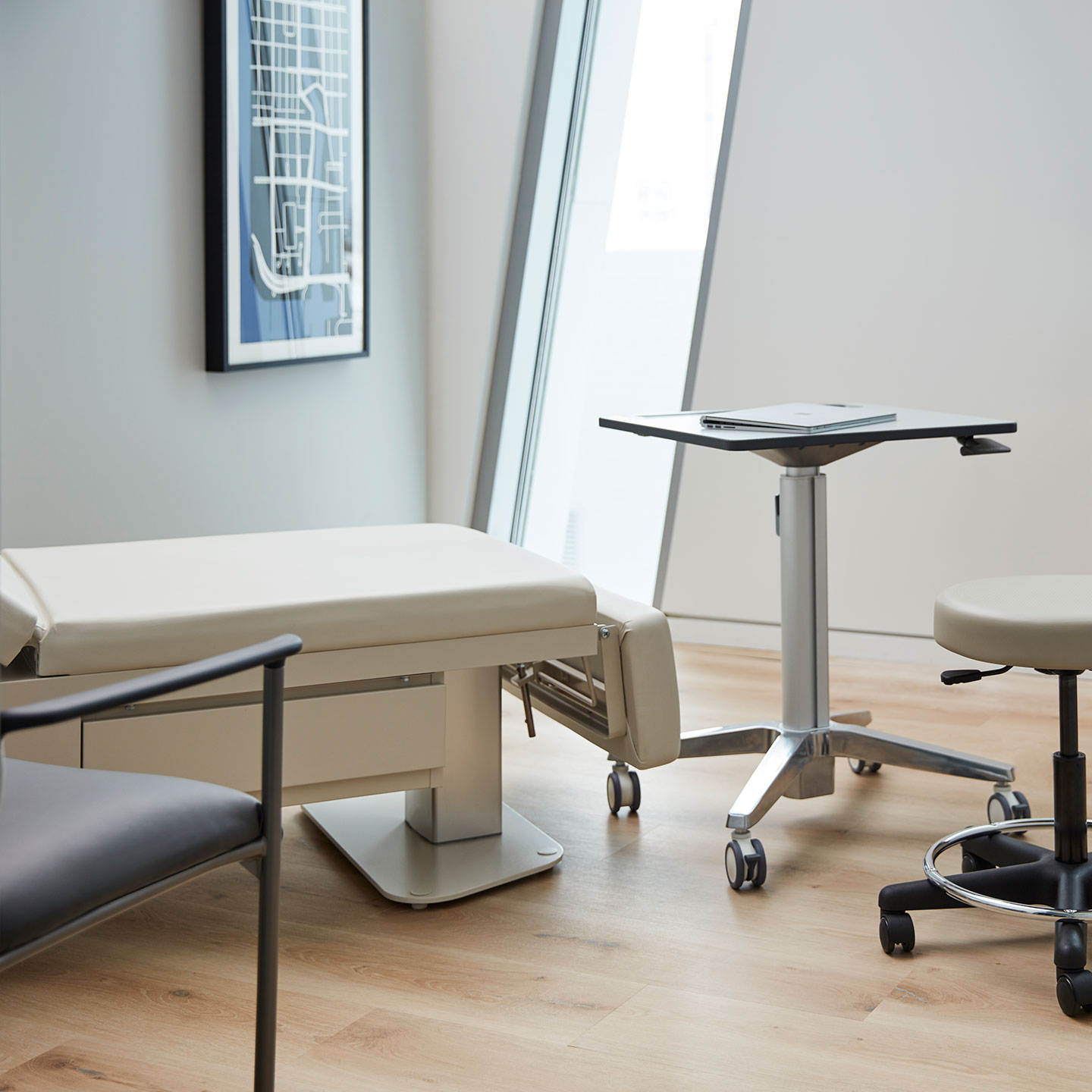 Haworth Power exam table with 2 height adjustable legs and a vinyl upholstery in an exam room with window