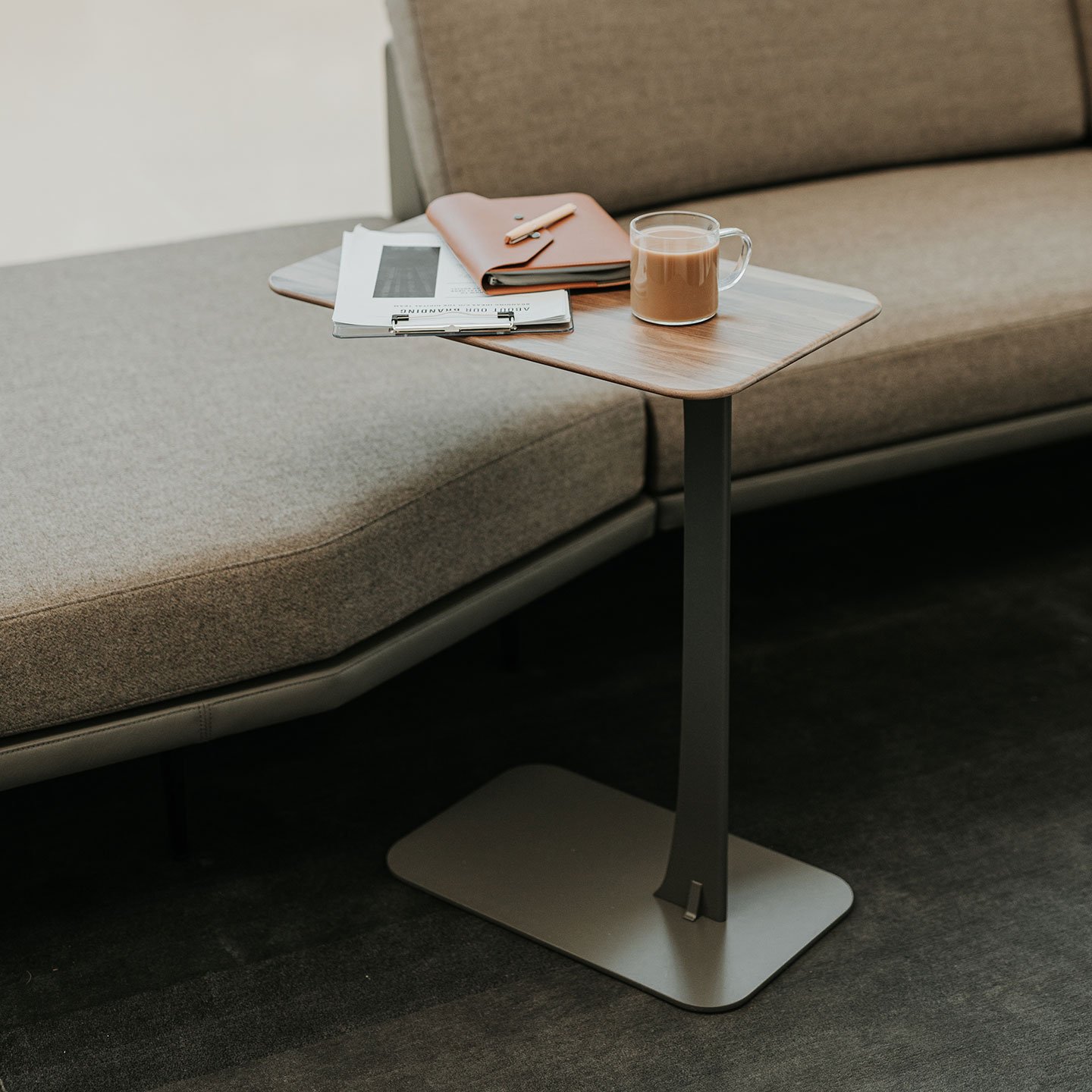 Haworth Larkin Table with white oak hardwood top and black base by a couch with coffee and a notebook on the table