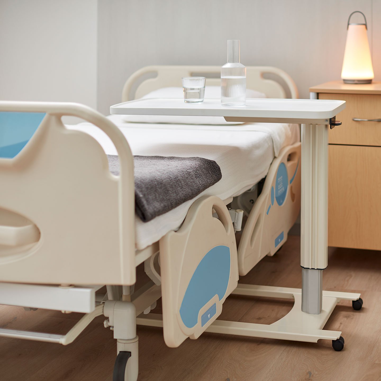 Haworth Overbed Table over a hospital bed in a hospital room with a glass of water on the table