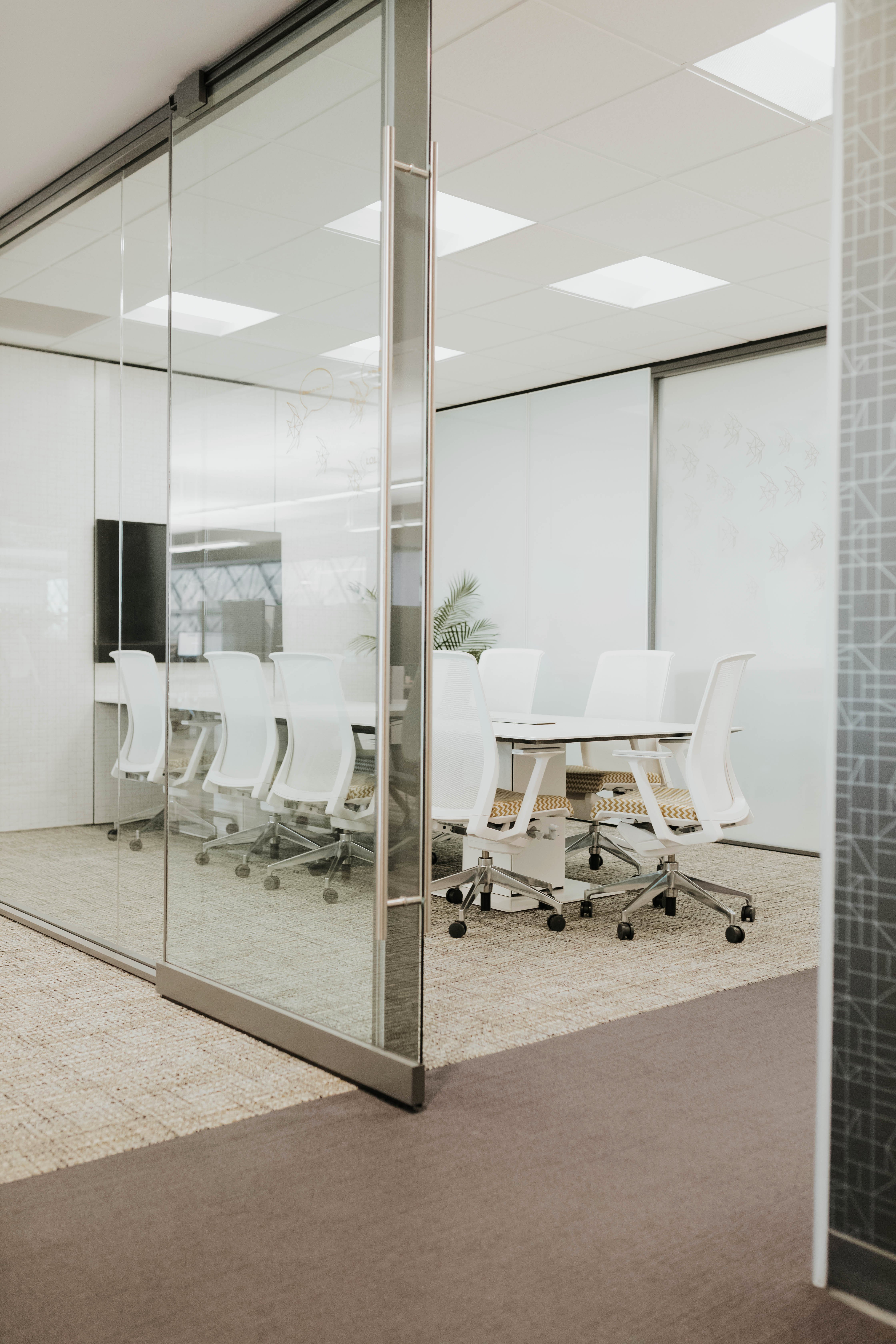 Haworth Planes Conference Table in a office closed meeting room with white boards and white chairs with a TV