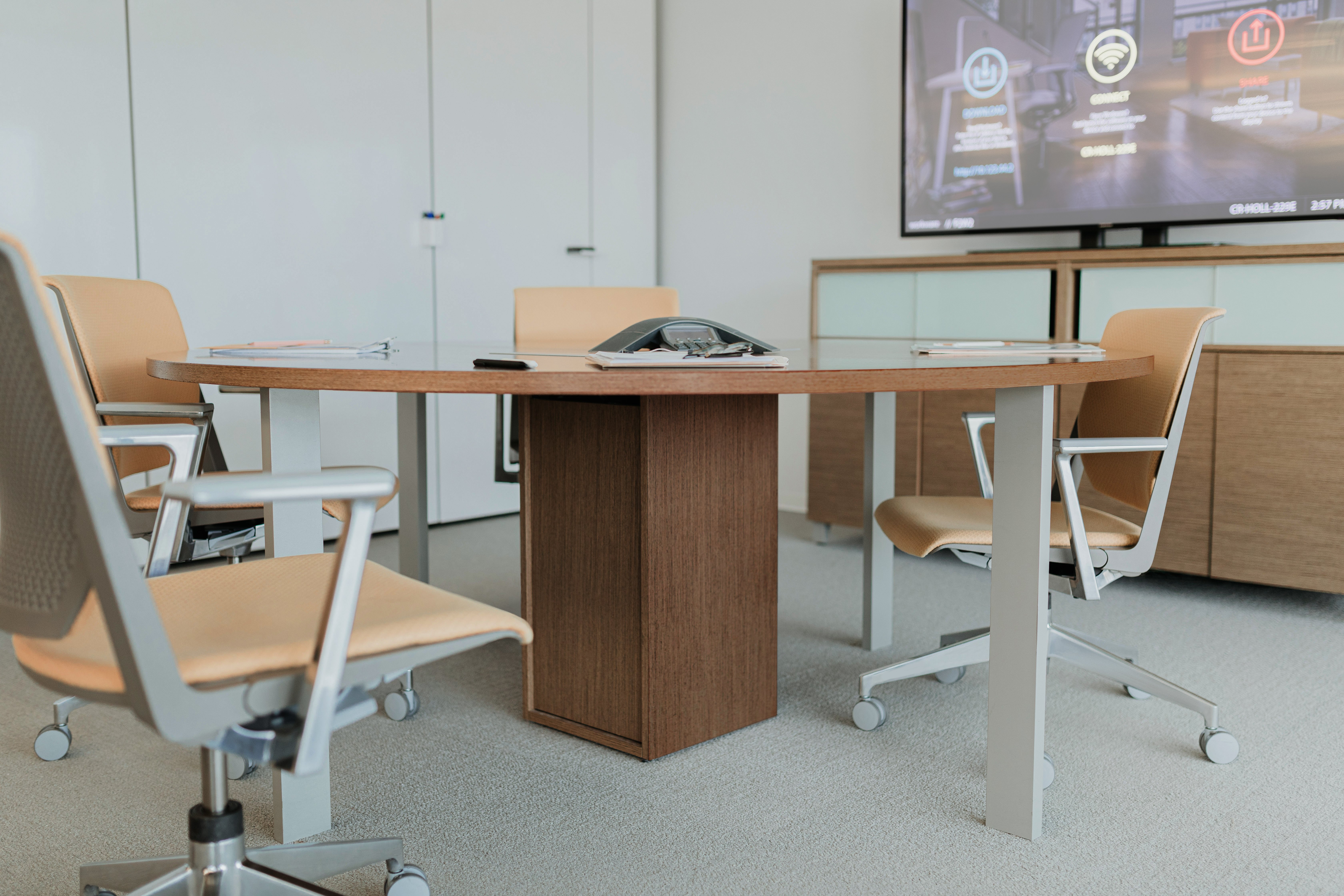 Haworth Planes Large Conference table in a closed meeting room with 4 chairs for employees and a monitor