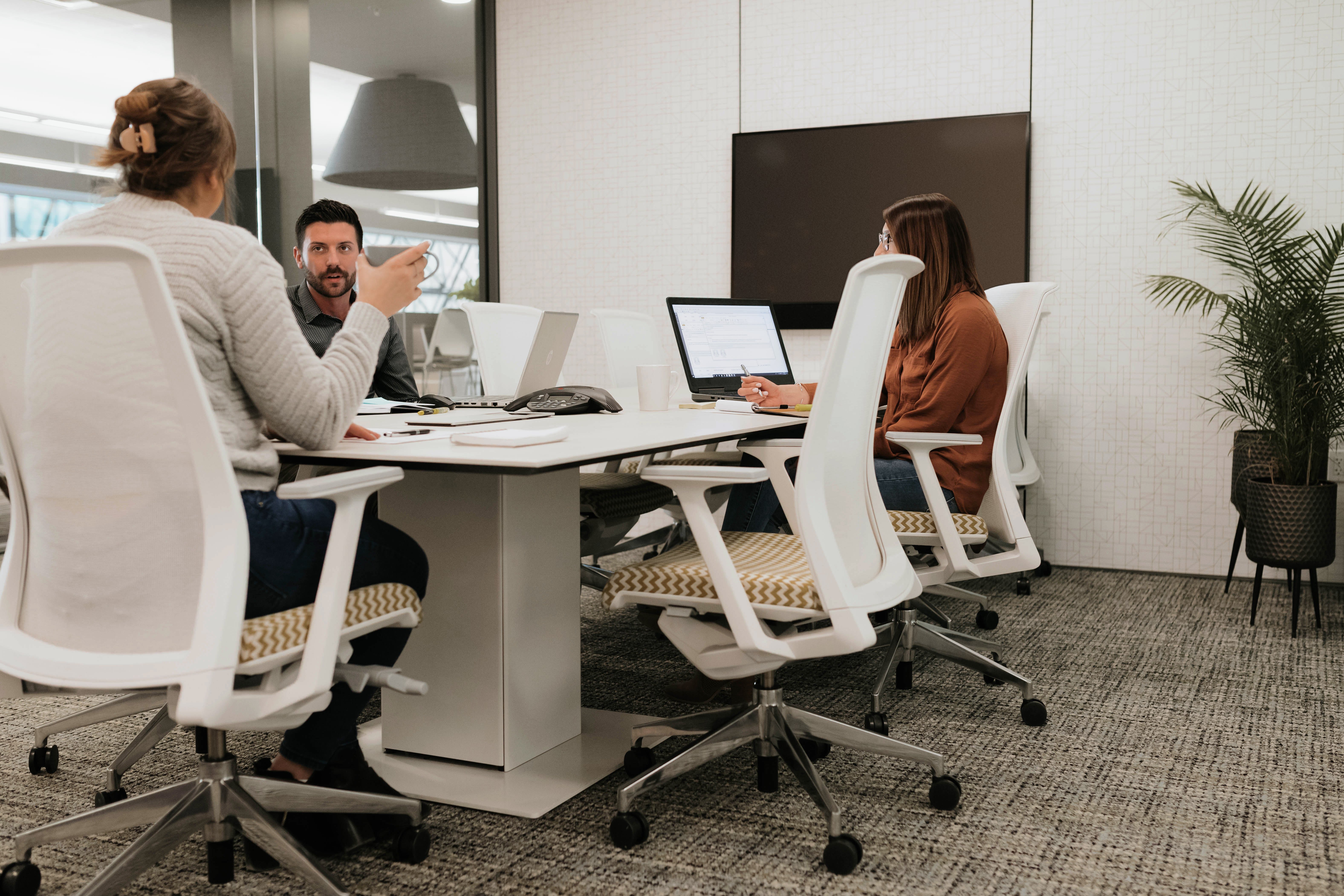 Haworth Planes Conference Table in a office closed meeting room with white boards and white chairs with a monitor and employees working