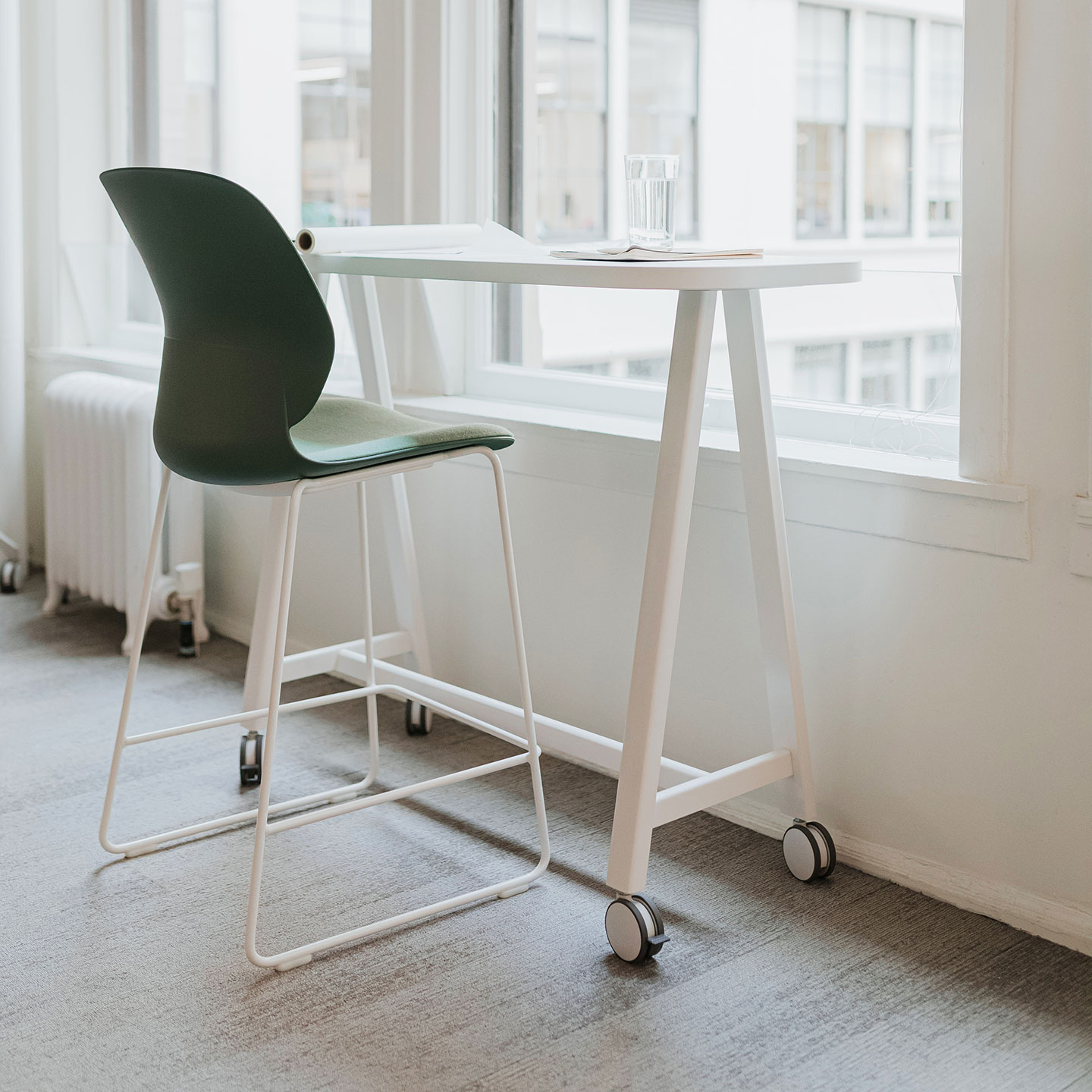 Haworth PopUp Table being used as a standing office desk in a open setting looking outside with book and water on table