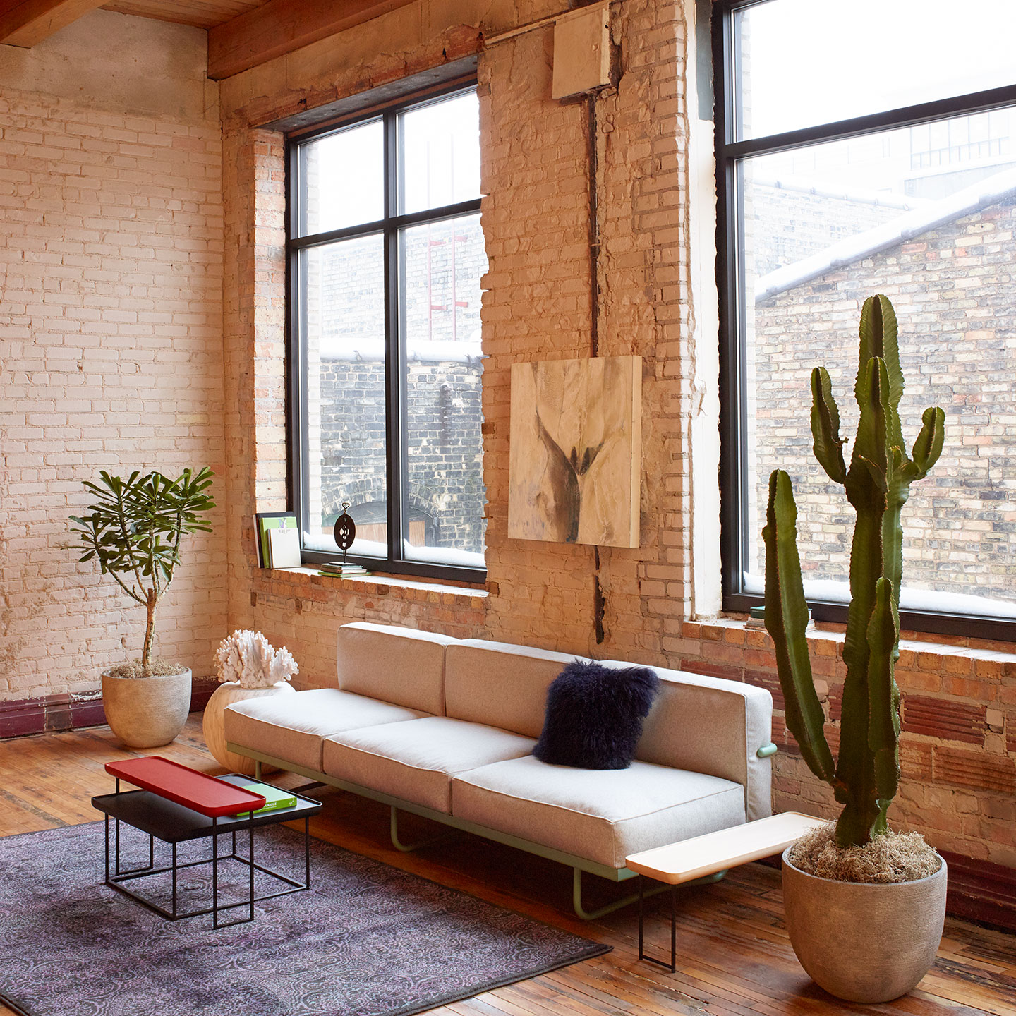 Haworth Torei table in black stained ash and red stained ash in home living room with a couch and a cactus