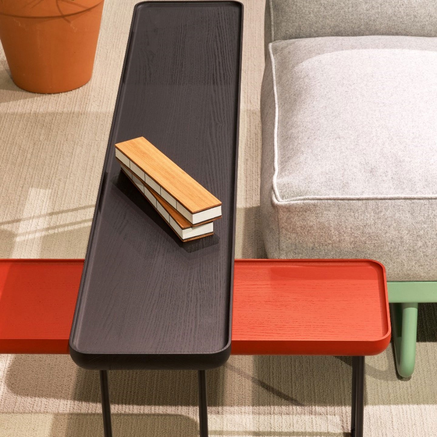 Haworth Torei Table in black stained ash and red stained ash next to couch as a side table