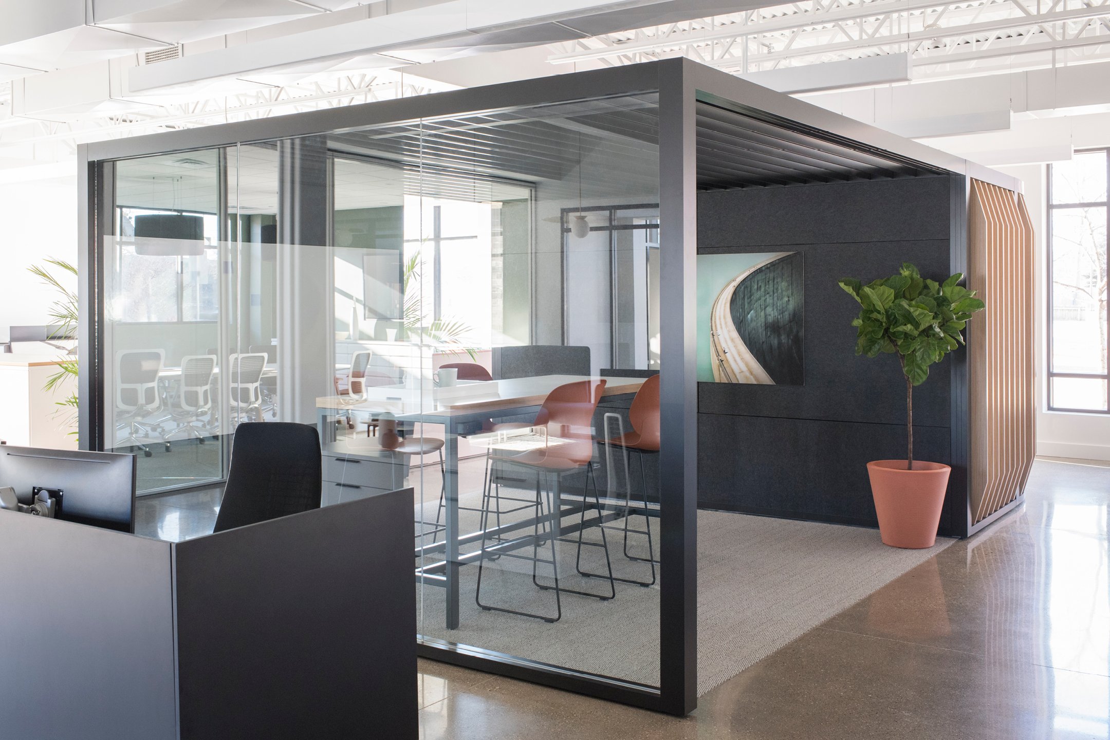 Haworth Pergola Workspace with black foundation and wood slits with a tall table and chairs inside for collaboration in open office space