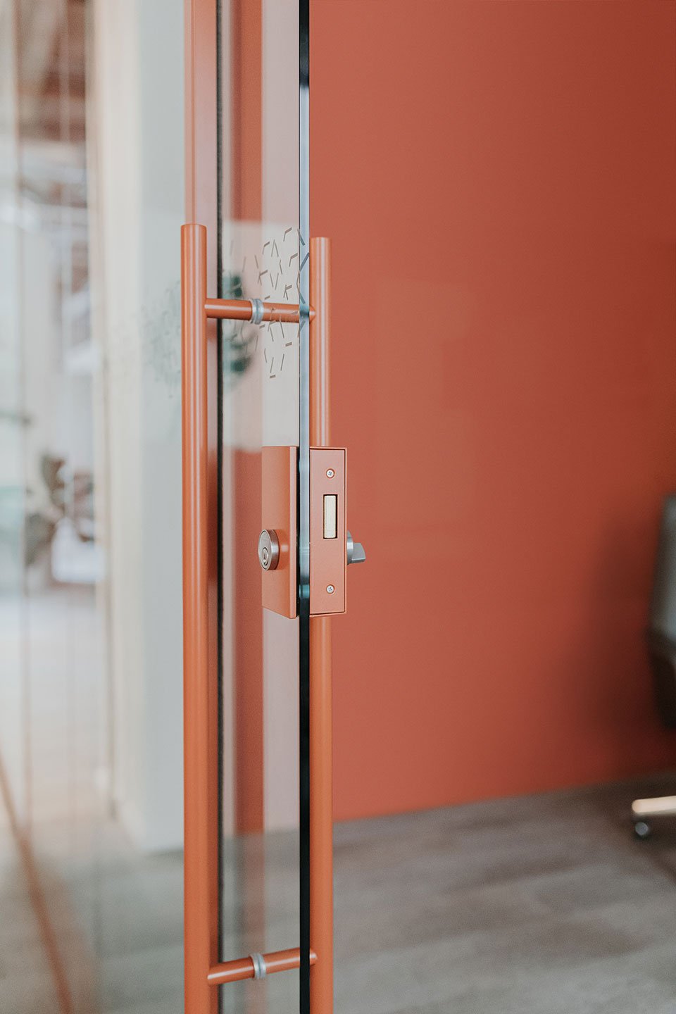 Haworth Trivati Wall with a sliding glass door with orange trim and door handle and orange wall