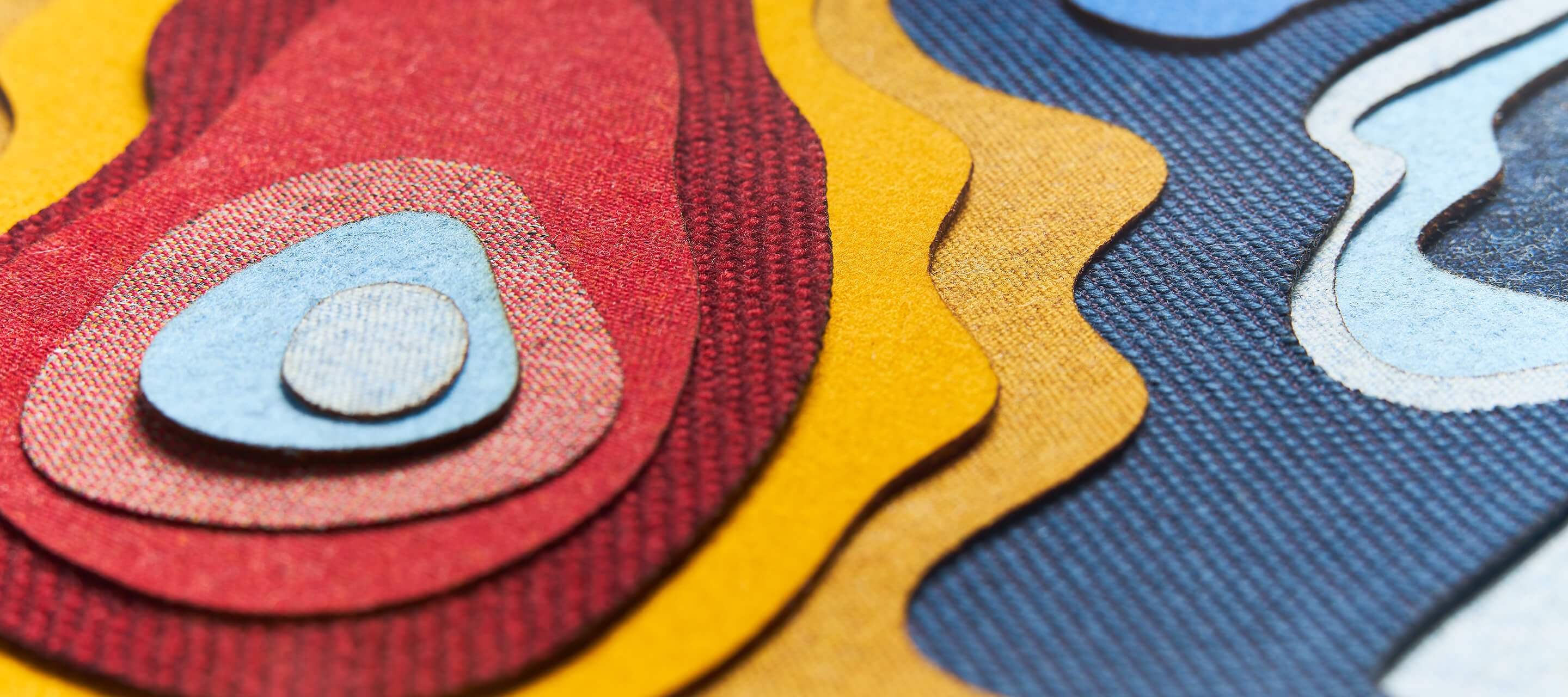 Haworth Kvadrat Banner Surfaces showing small cut outs of fabric in red yellow and blue colors with different patterns