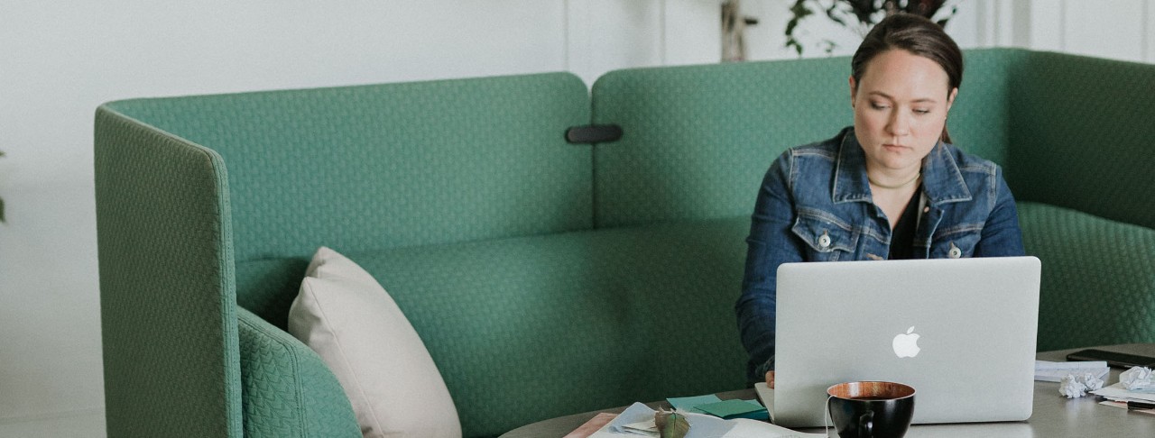 Woman sitting in teal Cabana Lounge chair while working on computer